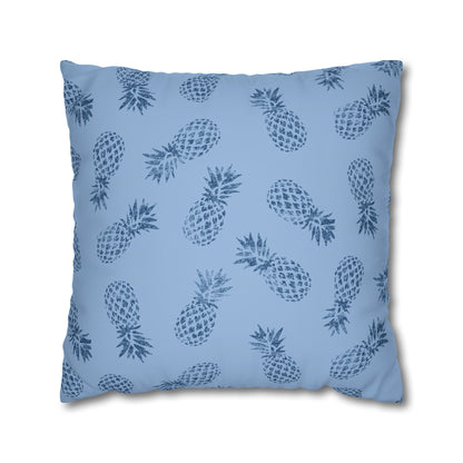 A square throw pillow featuring a repeating dark blue pineapple pattern on a light blue background, shown against a plain white studio backdrop.