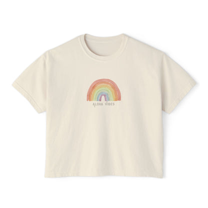 An off-white short-sleeve crop top t-shirt featuring a pastel rainbow graphic on the chest with the text 'ALOHA VIBES' underneath, displayed on a clean white background.