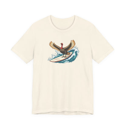 Natural cream Surfing Turkey graphic T-shirt featuring a turkey riding a surfboard on a blue ocean wave.