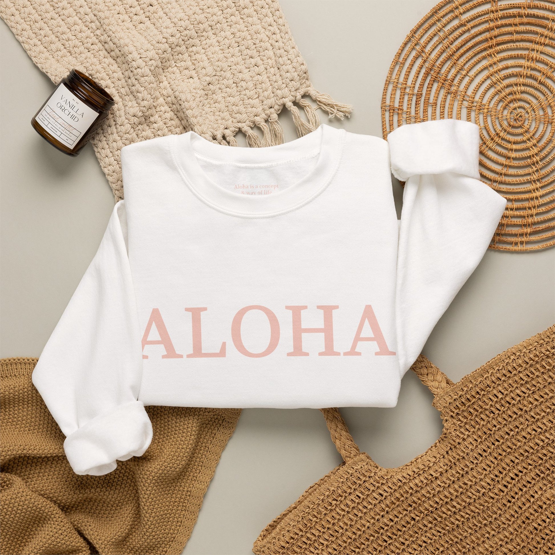 White sweatshirt folded with text 'ALOHA' in light pink