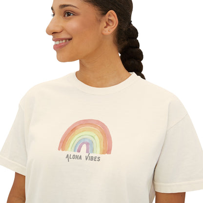 A woman wearing a white crewneck t-shirt with a watercolor rainbow graphic and the text 'ALOHA VIBES' printed below it, shown against a plain white background.