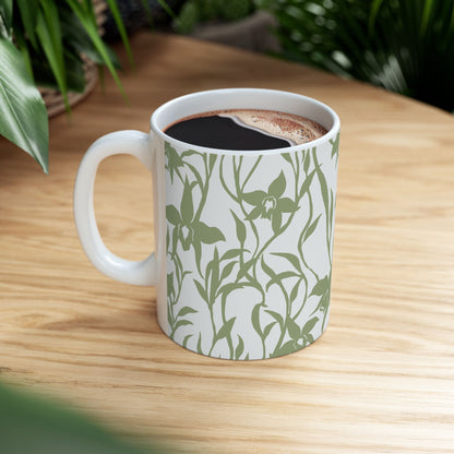 Orchid Sage coffee mug with tropical orchid print by Global Village Kailua sitting on wood table with green plants.