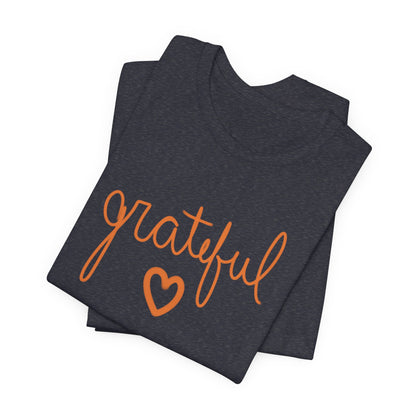 A folded heather navy t-shirt with the word 'grateful' written in orange cursive script and a matching orange heart underneath, displayed on a clean white background.