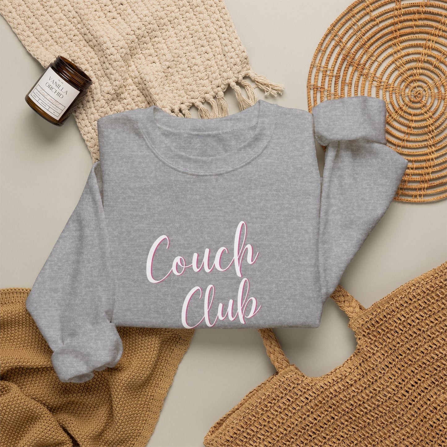 Folded gray sweatshirt with a graphic design text 'Couch Club' on a textured surface