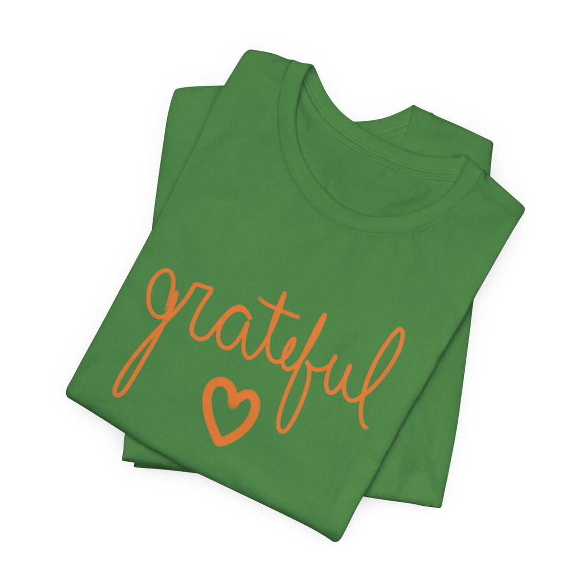 A folded green t-shirt with the word 'grateful' written in orange cursive script and a matching orange heart outline underneath, shown on a plain white background.