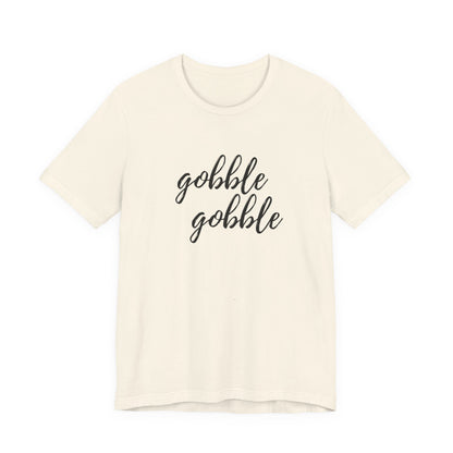 An off-white short-sleeve crewneck t-shirt featuring the phrase 'gobble gobble' printed in black cursive script across the chest, displayed against a solid white background.