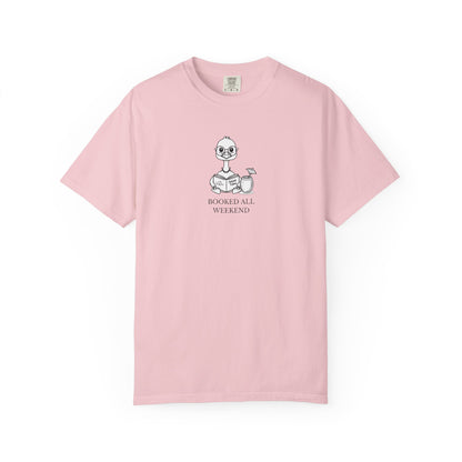 A light pink short-sleeve crewneck t-shirt with a small graphic of a nene goose reading a book and the text 'BOOKED ALL WEEKEND' printed on the chest, displayed on a clean white background.