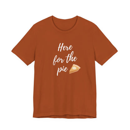 A rust-orange short-sleeve t-shirt with a white script graphic reading 'Here for the pie' next to a small slice of pie illustration, displayed on a solid white background.