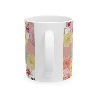A white ceramic coffee mug featuring a vertical tropical floral print with pink, yellow, and red hibiscus flowers on a dusty pink background.
