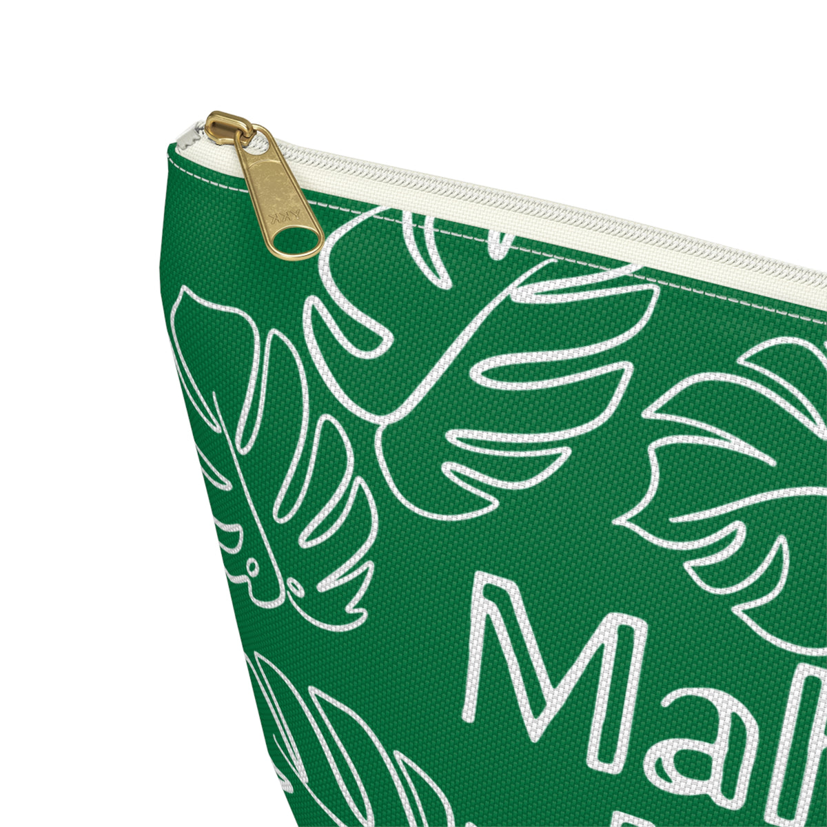 Close-up of a green zip pouch with a white monstera leaf pattern and partial white text, featuring a gold-tone zipper pull on a white background.