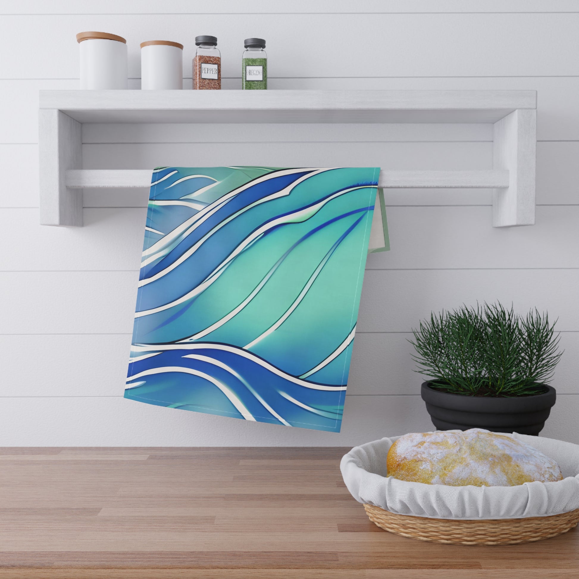A kitchen towel with a blue and teal wavy pattern hanging from a white wall rack in a bright kitchen setting.