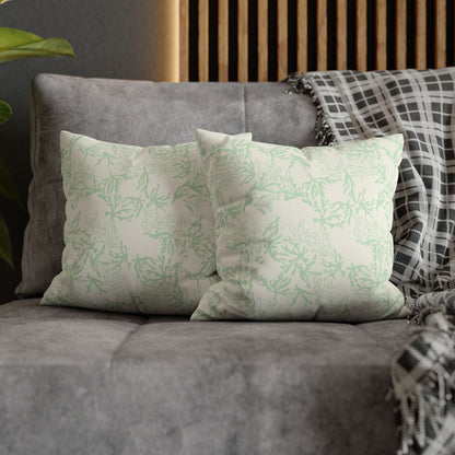 Two decorative pillows with sage coral branch patterns on a gray sofa.