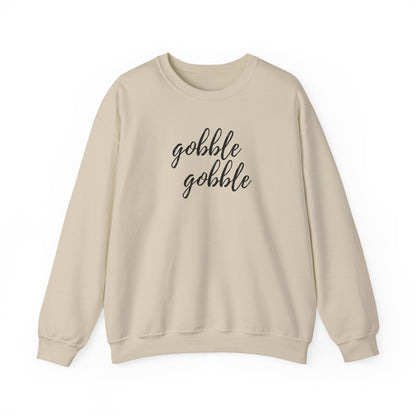 A beige crewneck sweatshirt with the words 'gobble gobble' printed in black cursive text across the chest, displayed on a clean white background.