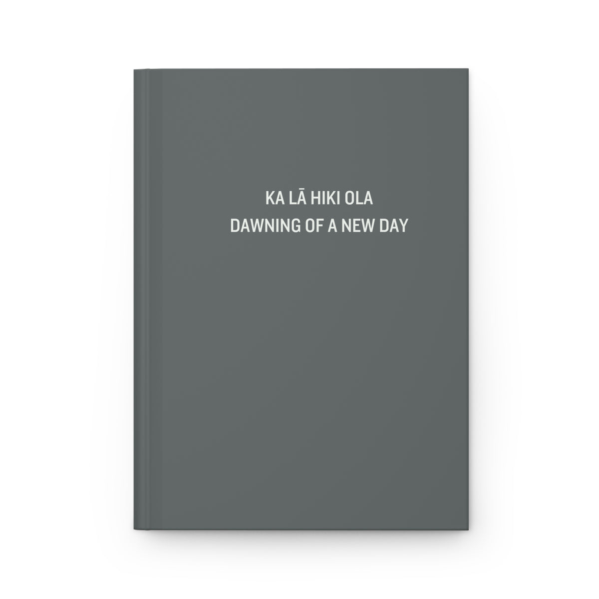 A dark gray hardcover notebook with white text on the front cover reading 'KA LÁ HIKI OLA DAWNING OF A NEW DAY', shown on a clean white background.