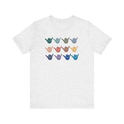 A white heather short-sleeve t-shirt with a graphic of nine shaka signs in various colors arranged in a 3x3 grid on the chest.