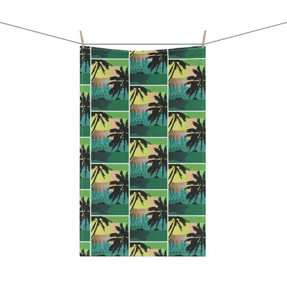 A tea towel with a repeating tropical sunset print 'KAILUA HAWAII' hangs from two wooden clothespins on a string against a plain white background.