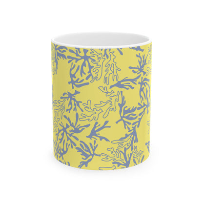 A white ceramic mug with a yellow exterior printed with a blue coral or seaweed pattern, shown against a plain white background.
