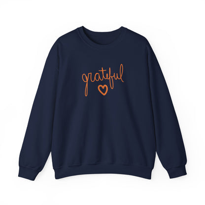 A navy crewneck sweatshirt featuring the word 'grateful' in orange cursive script and a matching orange heart outline on the chest, displayed against a solid white background.