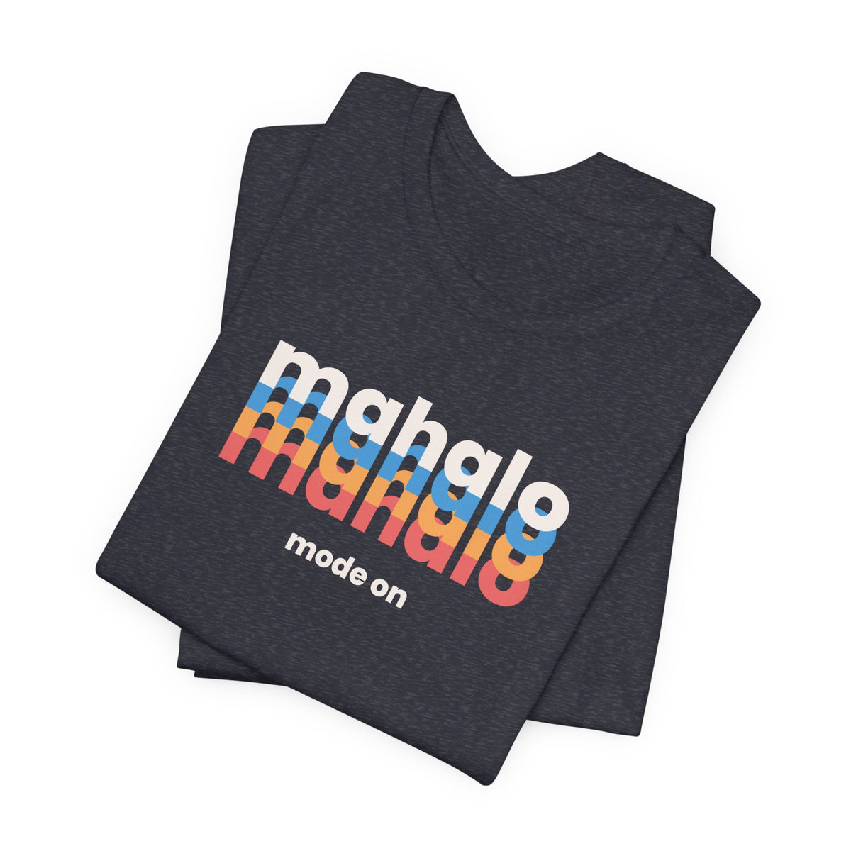 A folded dark heather navy t-shirt with a retro-style graphic reading 'mahalo mahalo' in white, blue, orange, and red gradient letters, with 'mode on' printed below in white, on a clean white background.