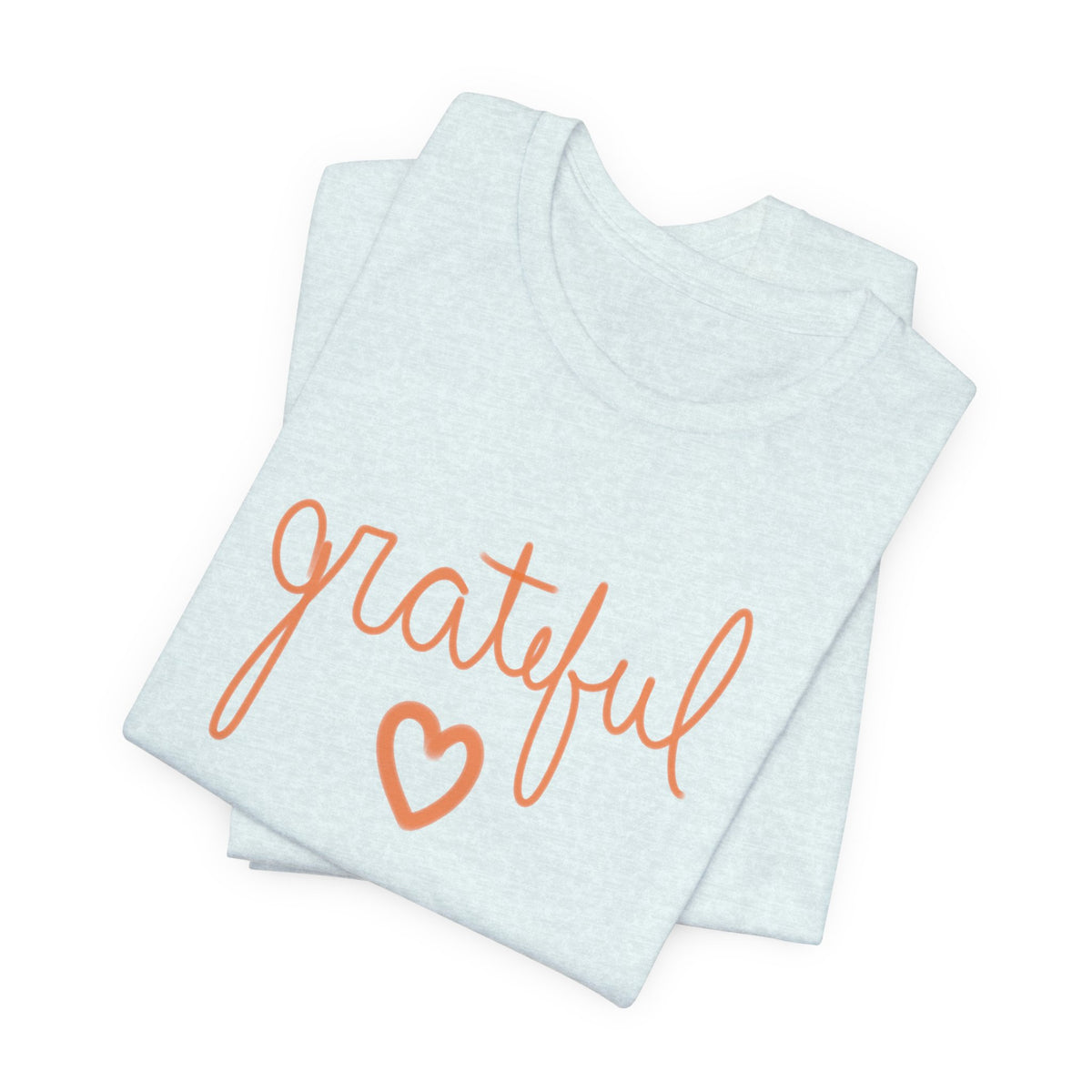 A folded light blue t-shirt with the word 'grateful' written in orange cursive script and a matching orange heart outline on the front, set against a plain white background.