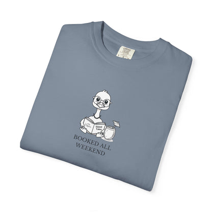 A blue comfort colors t-shirt with design of a nene goose reading a book and text 'booked all weekend' folded