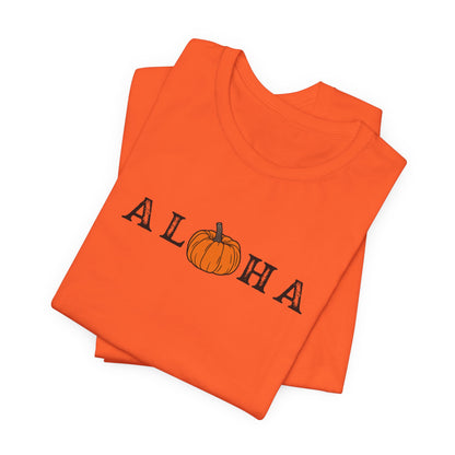 A folded bright orange t-shirt featuring the word 'ALOHA' in black block letters, where the letter 'O' is replaced by a small orange pumpkin illustration with a brown stem. The shirt is photographed on a clean white background.