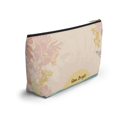 A rectangular zippered pouch with a cream background and a floral sunburst pattern in soft pink, gold, and light purple. The bottom right corner features a yellow semi-circle with the text 'Glow Bright' in black script.