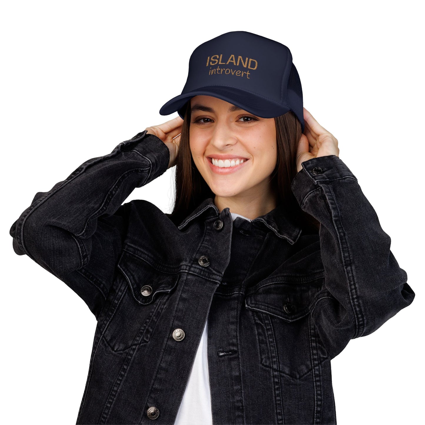 Person wearing a navy cap with a tan embroidery 'island introvert' and a black denim jacket on a white background