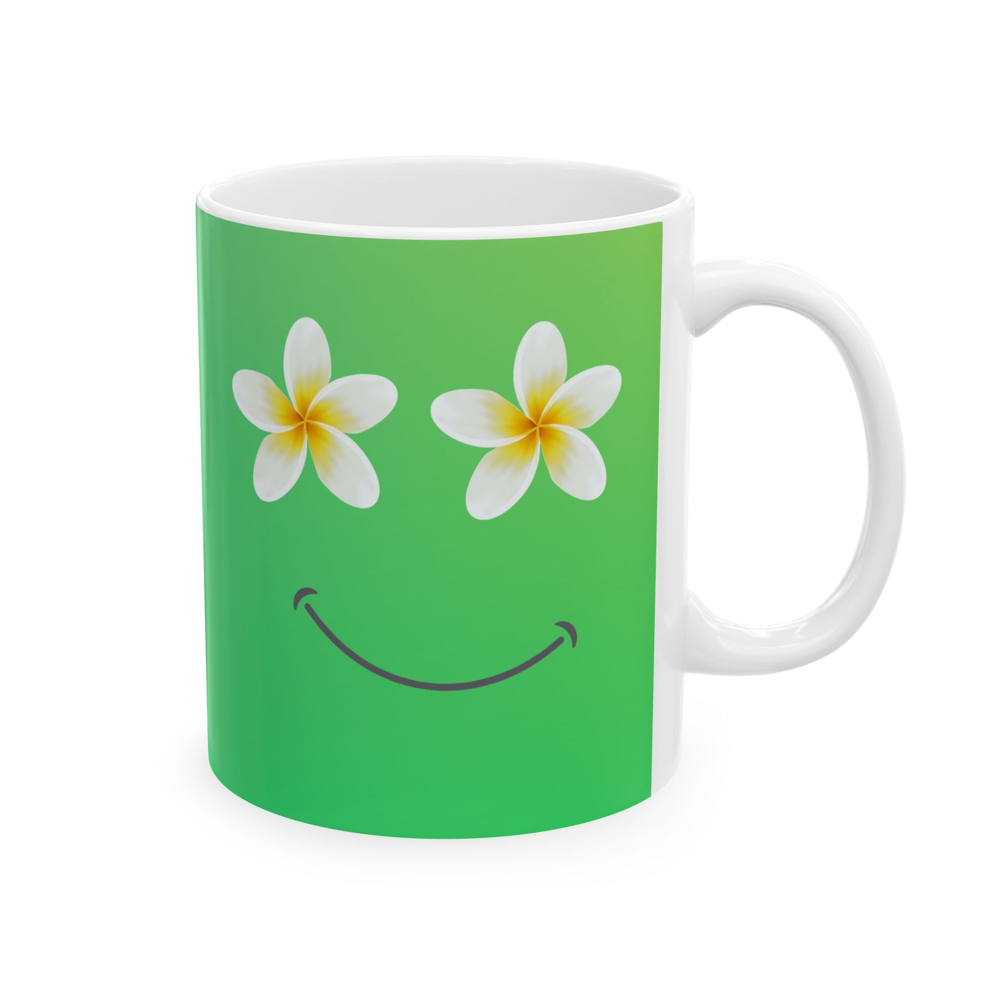 A white ceramic mug with a green printed design featuring two white plumeria flowers for eyes and a black smiley mouth.