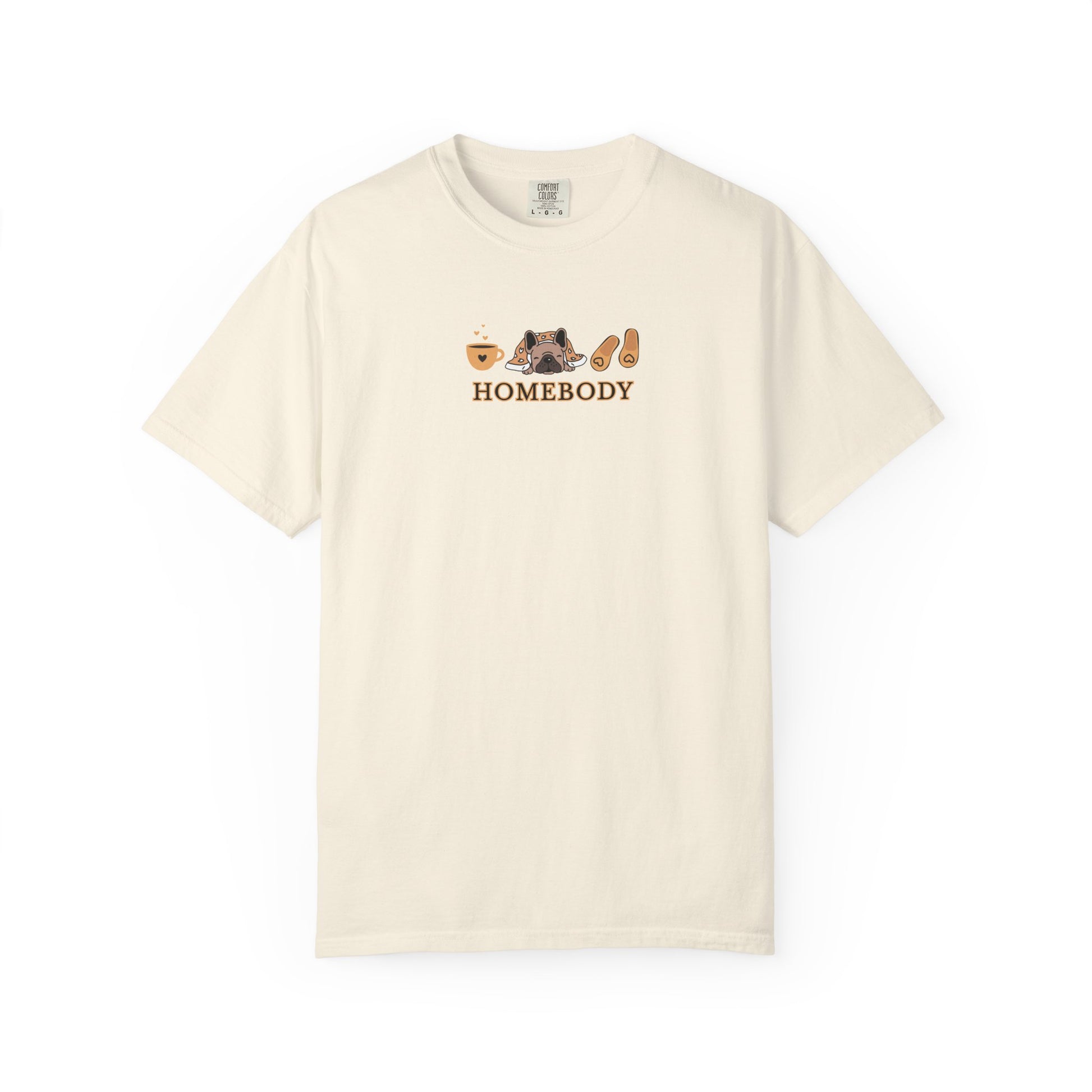 An off-white short-sleeve crewneck t-shirt with a graphic on the chest depicting a dog under a blanket, a coffee mug, a pair of house slippers, and the word 'HOMEBODY' in brown text.