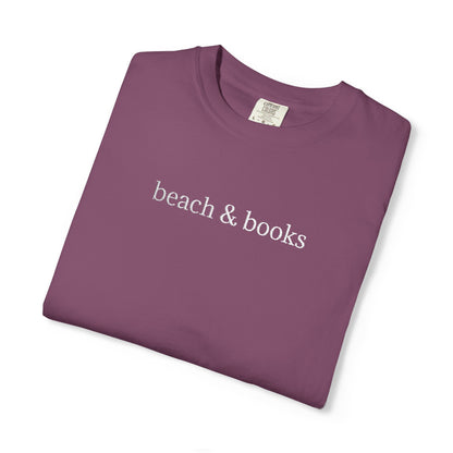 A folded purple comfort colors tee with 'beach & books' embroidered in white