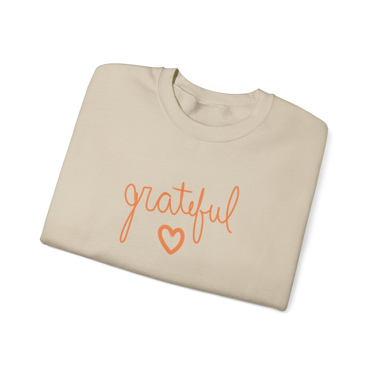 A beige crewneck sweatshirt folded neatly, featuring the word 'grateful' in orange cursive script and a matching orange heart outline on the front, set against a plain white background.