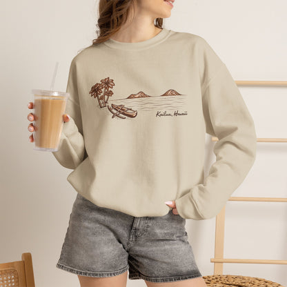 Woman standing wearing Tonal hand-drawn Kailua canoe and Mokulua Islands unisex sweatshirt in warm neutral shades holding an iced coffee.