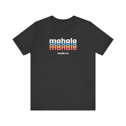 A dark heather gray short-sleeve t-shirt with a colorful graphic on the chest reading 'mahalo made on' in white, light blue, orange, and red, with 'mode on' printed below in white.