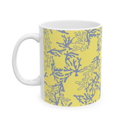A white ceramic mug featuring a yellow and blue coral pattern on the exterior, with a white interior and handle, shown against a plain white background.