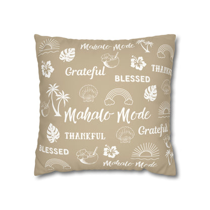 A square throw pillow in a warm beige color, printed with white tropical-themed illustrations and words including 'Mahalo Mode', 'Grateful', and 'Blessed'.