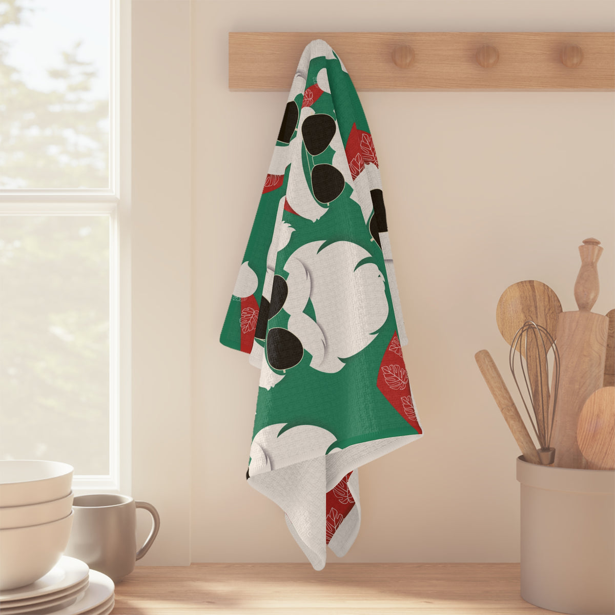 Cool Santa Aloha Kalikimaka kitchen towel with sunglasses Santa, tropical greenery and Christmas ornaments hanging off of wood peg in a kitchen