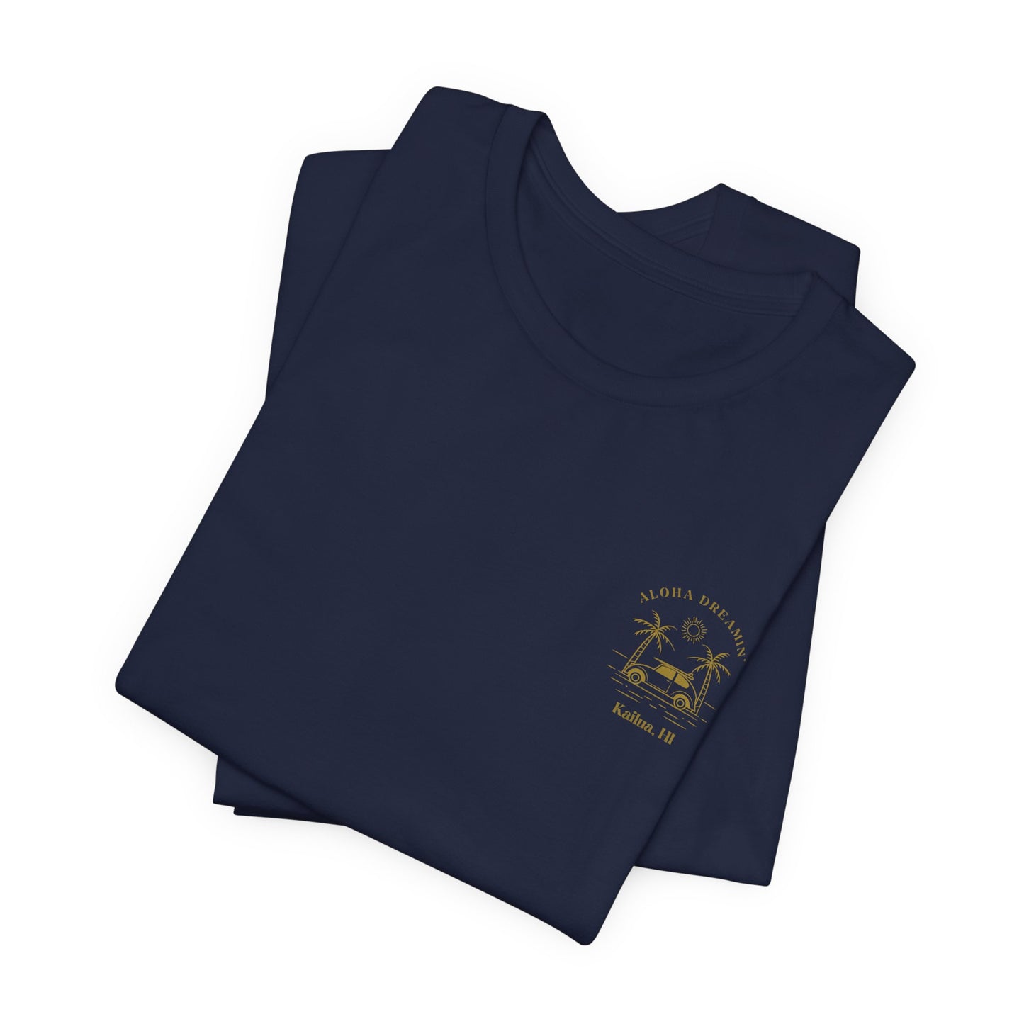 A folded navy short-sleeve t-shirt shown from the front, featuring a gold-colored retro graphic of a classic car between two palm trees with the text 'ALOHA DREAMIN'' and 'Kailua, HI' on the left chest.