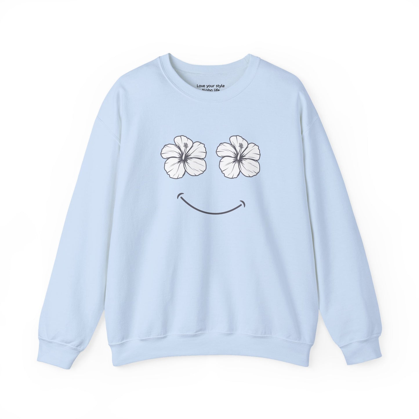 A light blue crewneck sweatshirt featuring a graphic print of two white hibiscus flowers forming eyes and a black smiley mouth on the front.
