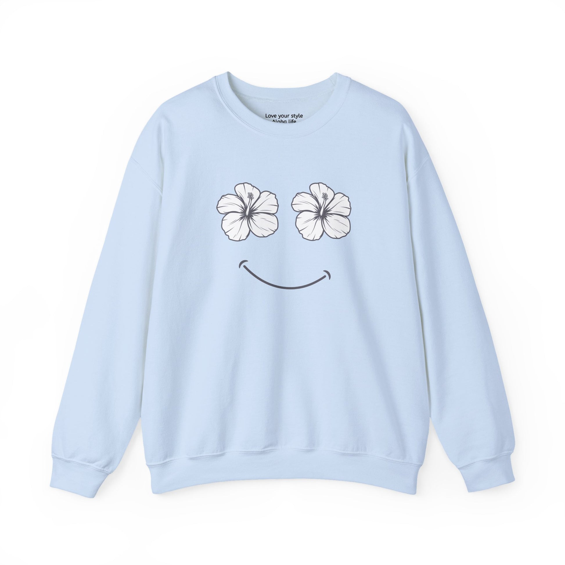 A light blue crewneck sweatshirt featuring a graphic print of two white hibiscus flowers forming eyes and a black smiley mouth on the front.