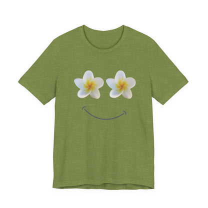 An olive green short-sleeve t-shirt with a graphic of two white plumeria flowers with yellow centers acting as eyes, and a simple smiley mouth underneath, shown on a plain white background.