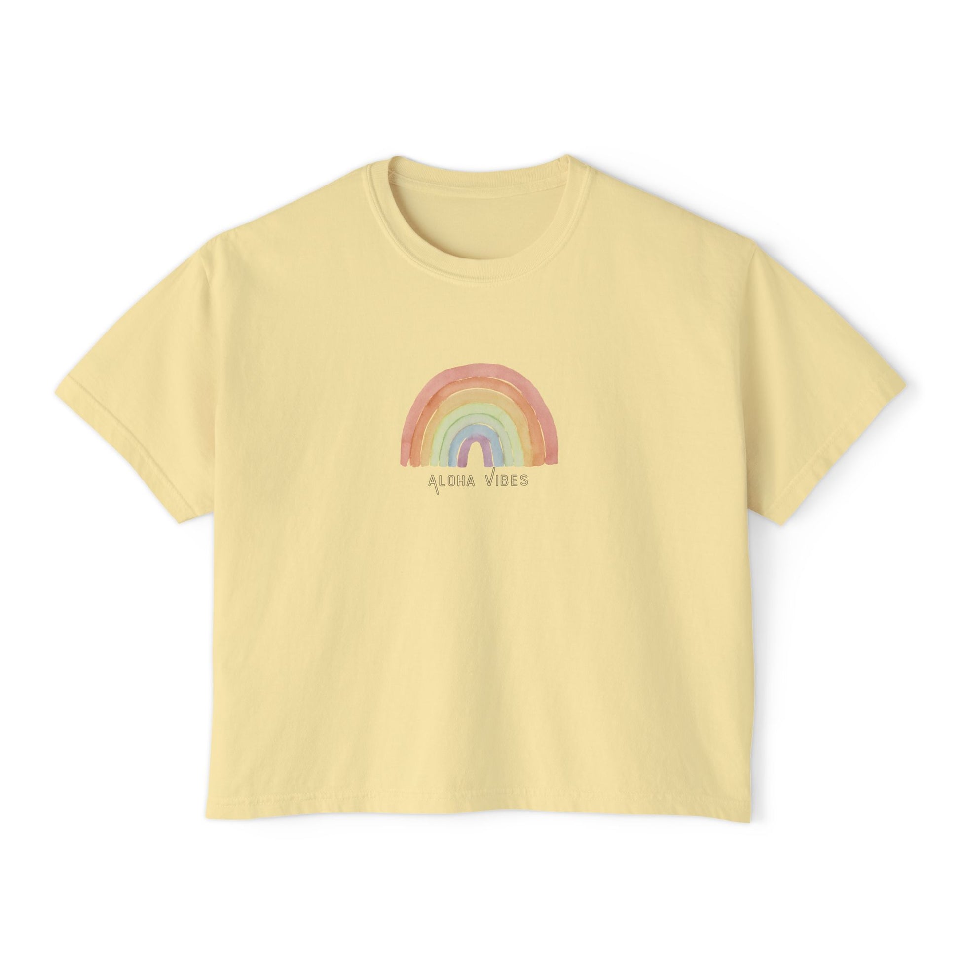 A pale yellow short-sleeve crop top t-shirt featuring a pastel rainbow graphic and the text 'ALOHA VIBES' printed on the chest, displayed against a solid white background.