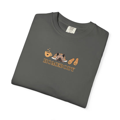 A folded dark gray short-sleeve crewneck t-shirt with a graphic on the chest depicting a dog under a blanket, a coffee mug, a pair of house slippers, and the word 'HOMEBODY' in brown text.
