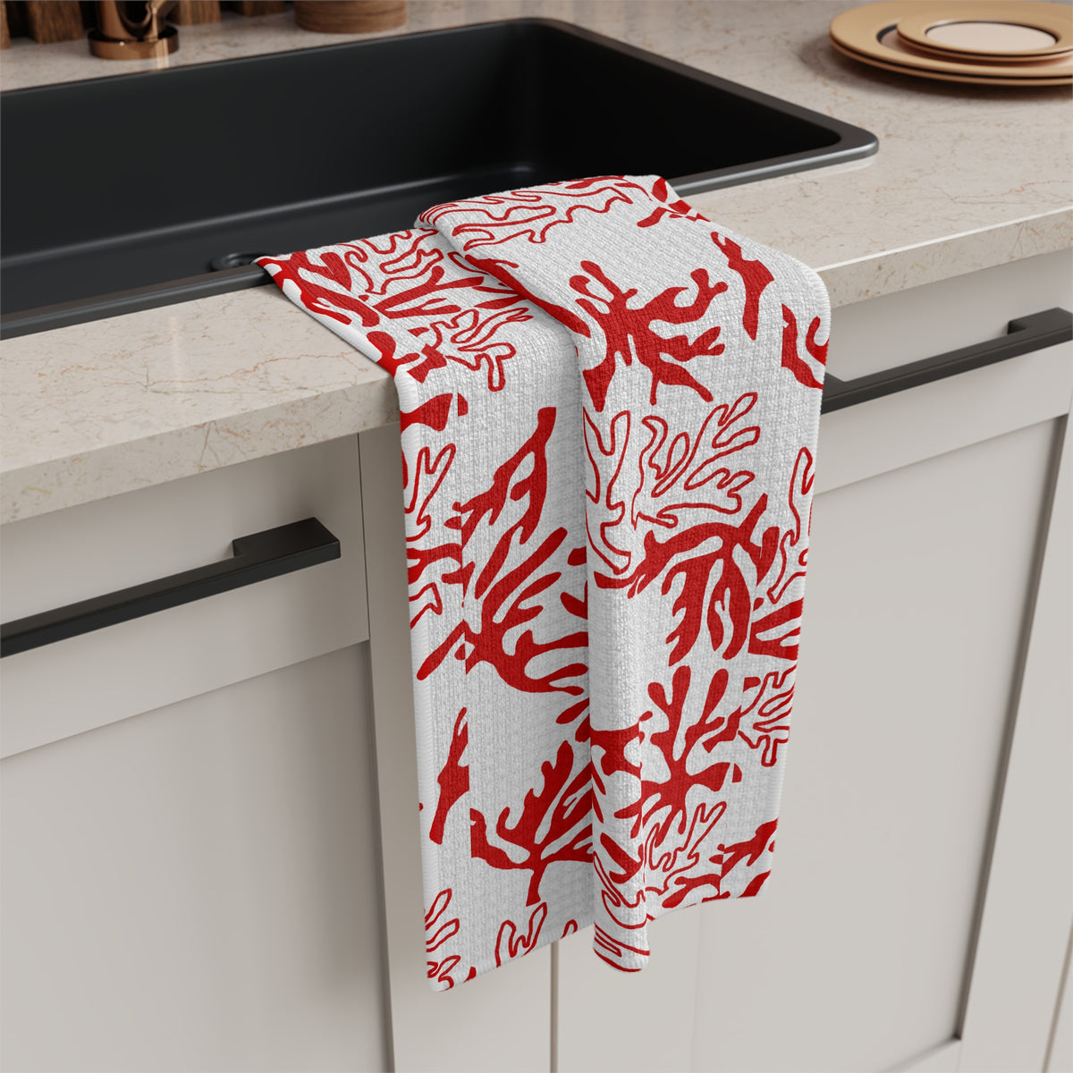 Red and white coral print Hawaiʻi kitchen towel with original Global Village pattern hanging off a kitchen sink
