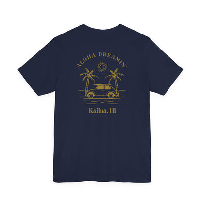 A navy short-sleeve t-shirt shown from the back, featuring a gold-colored retro graphic of a classic car between two palm trees with the text 'ALOHA DREAMIN'' and 'Kailua, HI'.