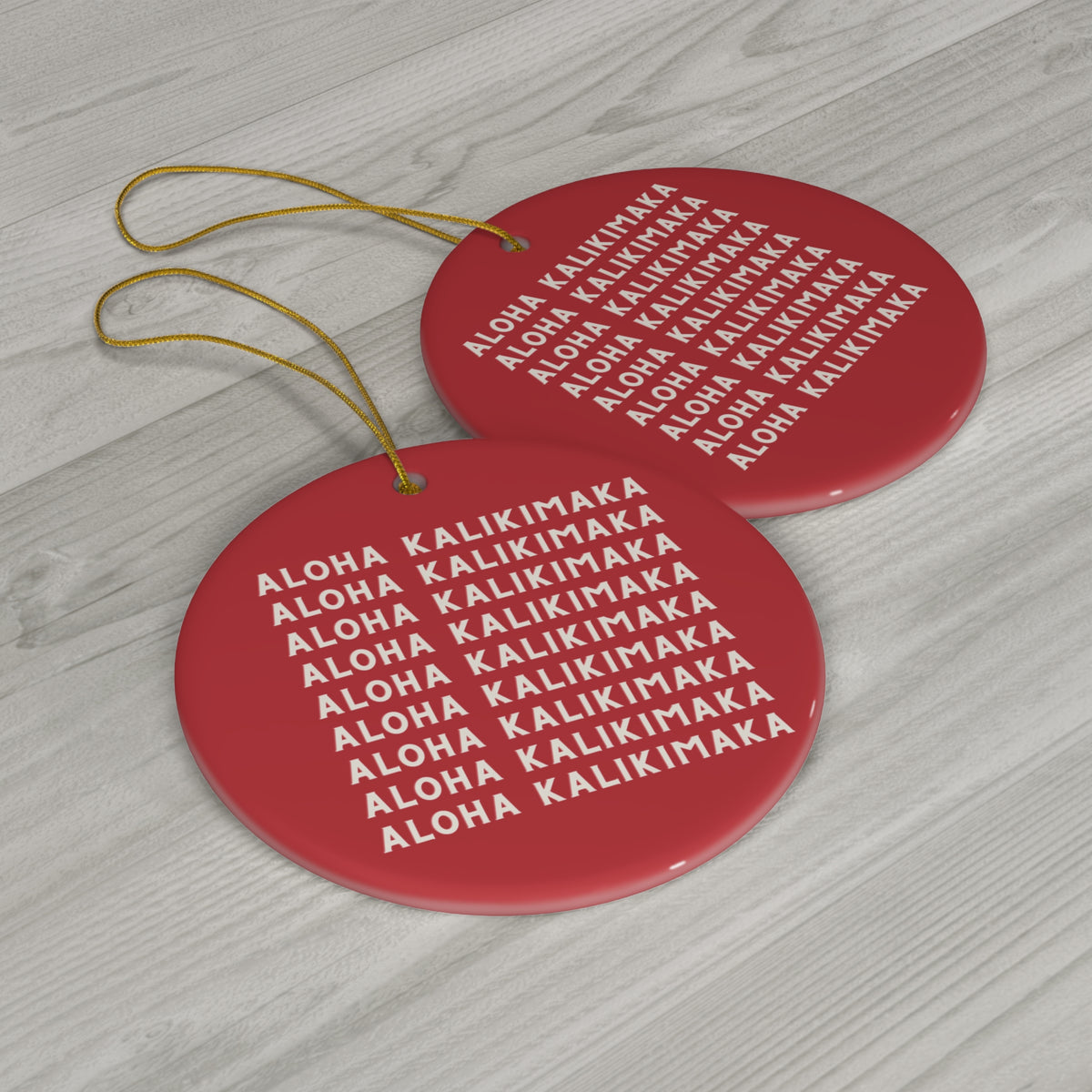 Red ceramic Christmas ornament featuring repeating cream Aloha Kalikimaka lettering on both sides.