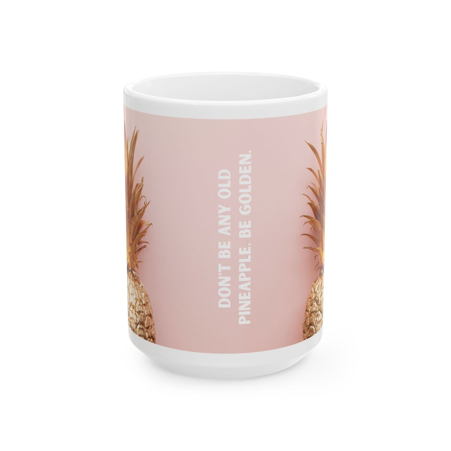 A white ceramic mug with a dusty pink wraparound design featuring partial pineapples on both sides and the vertical text 'DON'T BE ANY OLD PINEAPPLE, BE GOLDEN.' on the front.