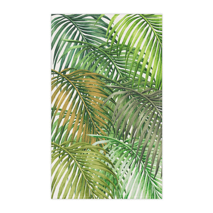 A rectangular tea towel featuring a tropical palm leaf pattern in shades of green, olive, and soft yellow on a white background.