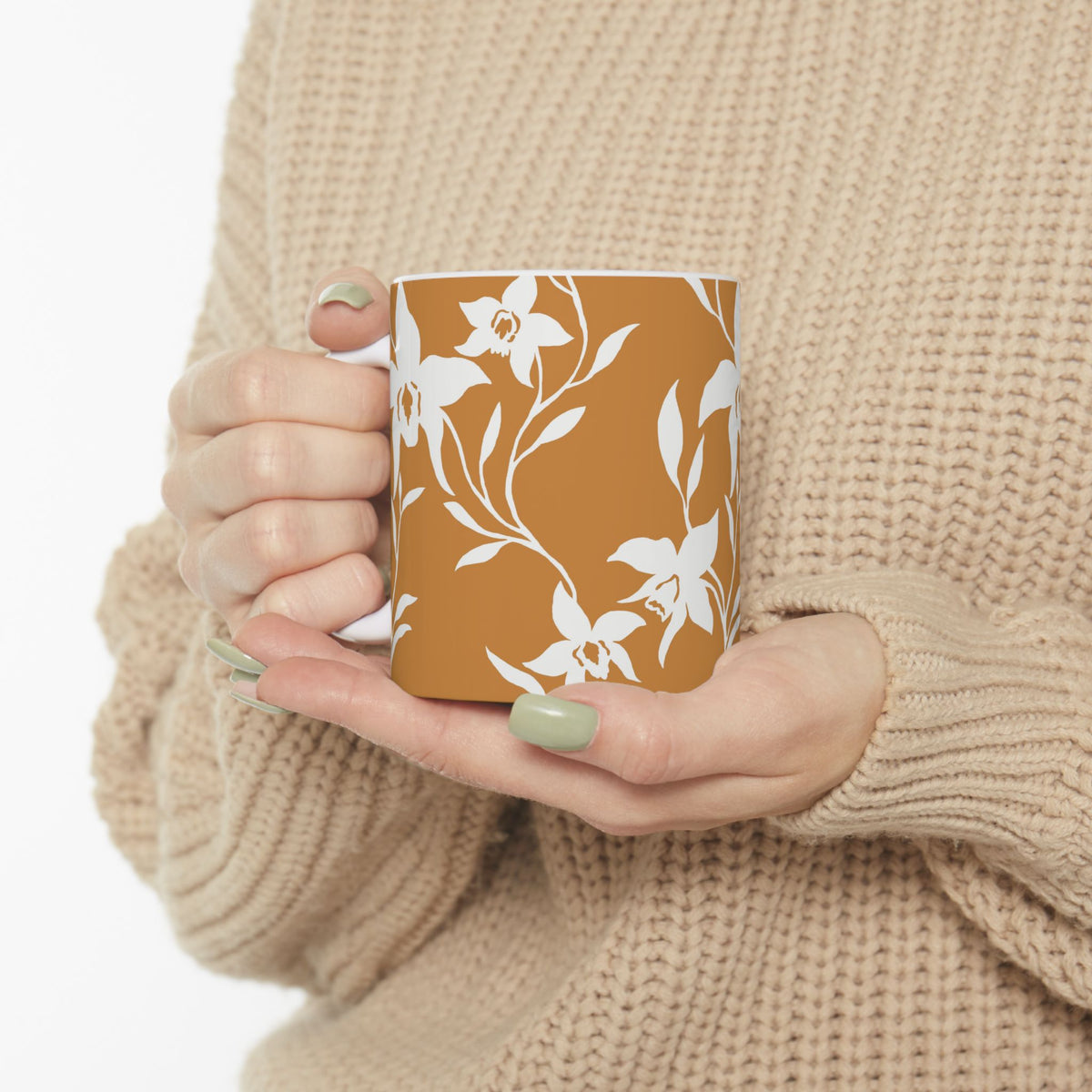 A woman in a tan sweater holding an Orchid Caramel coffee mug with white tropical orchid print by Global Village Kailua