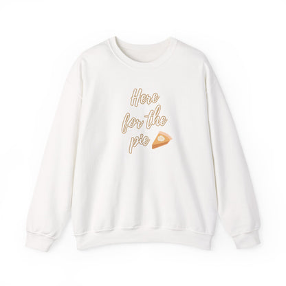 A white crewneck sweatshirt featuring a graphic print on the front with the text 'Here for the pie' in a light brown outline font next to a small slice of pie illustration.